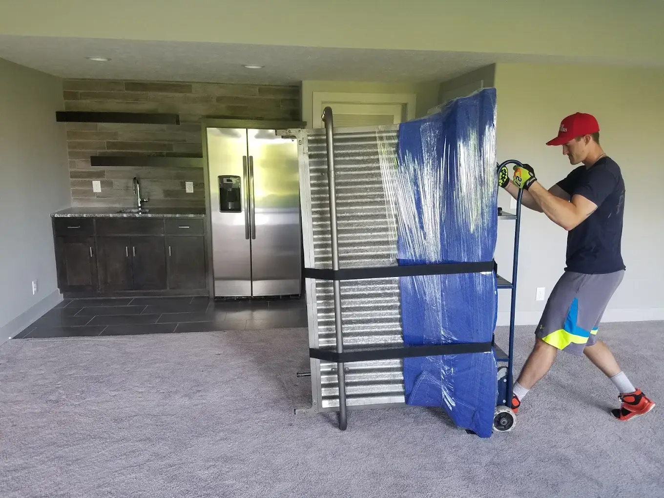 Mover using a hand truck to move a mattress wrapped and secured with straps